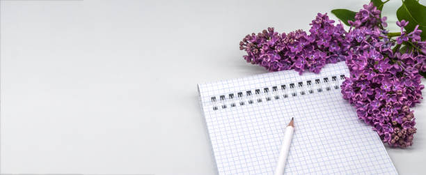 Spiral notebook and pen. Notepad with pen and flowers. Notebook lilacs on light background. stock photo