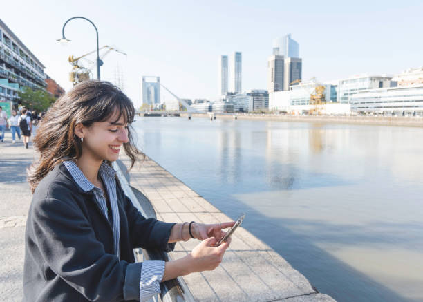 istock Young woman at the harbor using smart phone on a sunny day sending message. copy space 1346630668