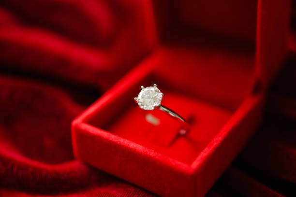 istock Diamond ring in jewelry gift box on red fabric background 1346635421