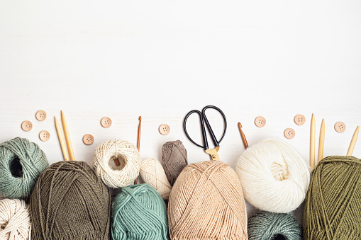 Craft hobby background with yarn in natural colors. Recomforting, destressing hobby for cold fall and winter weather. Mock up, copy space, top view