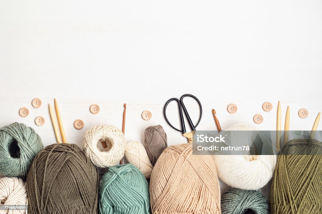 Craft hobby background with yarn in natural colors Craft hobby background with yarn in natural colors. Recomforting, destressing hobby for cold fall and winter weather. Mock up, copy space, top view Knitting Stock Photo