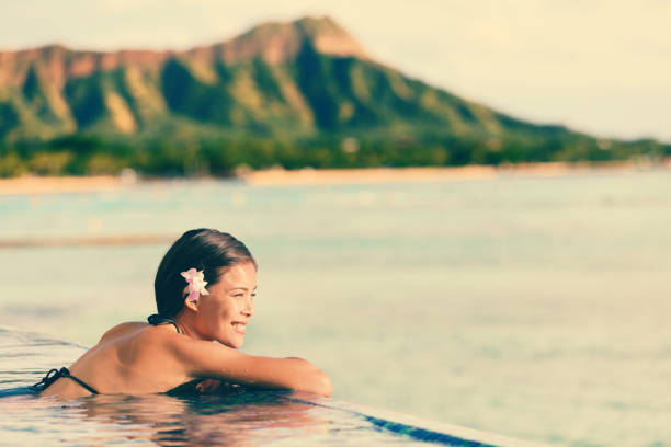 femme souriante se relaxant dans la piscine à débordement - waikiki beach photos et images de collection