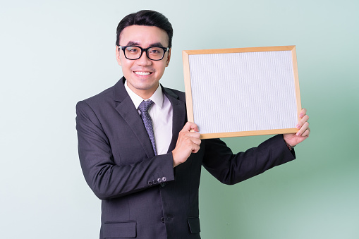 Young Asian businessman posing on green background