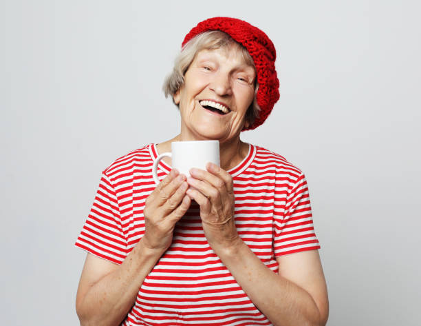 istock old excited lady smiling laughing, holding cup drinking coffee or tea 1346658939