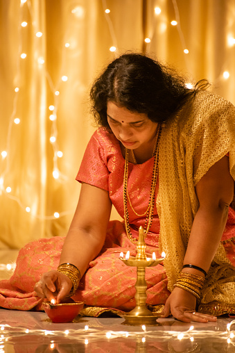 Indian women  holding Diwali oil lamp inside home with traditional dress