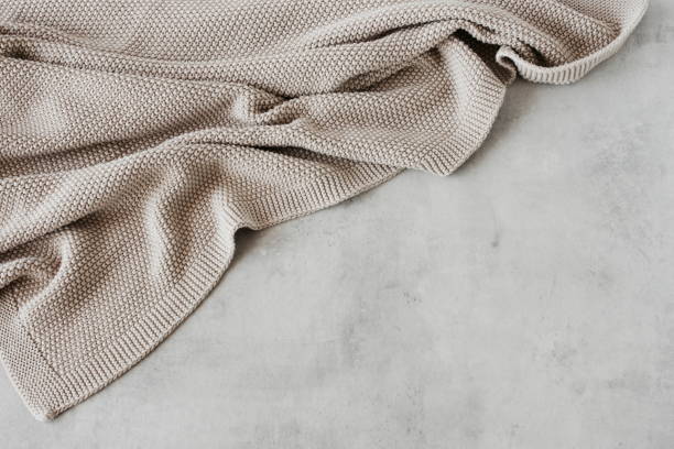 istock Beige knitted blanket on gray concrete background with copy space template. 1346666635