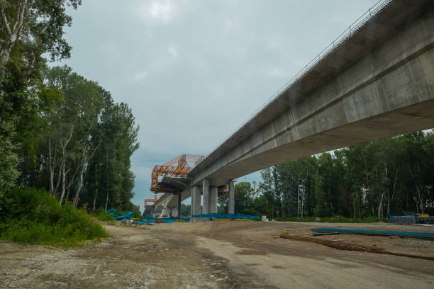 istock Motorway bridge construction on a dull day. Making a new concrete bridge over a river, view of construction site. 1346668804