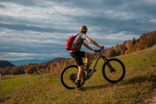 istock Young caucasian mountain biker resting and posing on sunny meadow in autunn setting. Visible mountains in the background. 1346670439