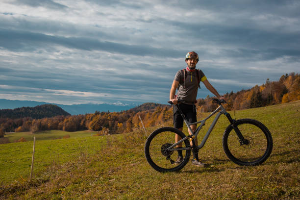 istock Young caucasian mountain biker resting and posing on sunny meadow in autunn setting. Visible mountains in the background. 1346670443