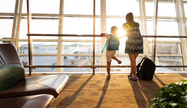 istock Mother and son looking through window in airport terminal 1346673783