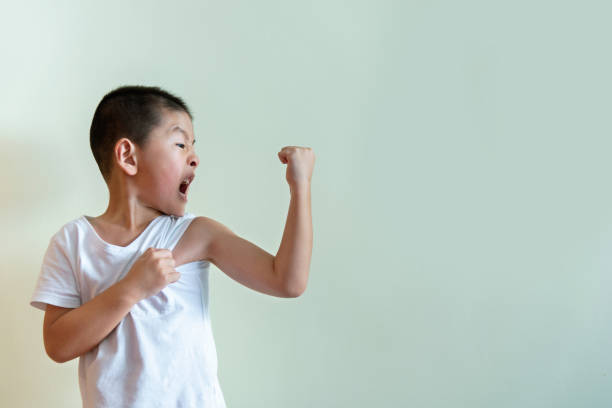 маленький мальчик показывает свой бицепс - flexing muscles little boys human muscle strength стоковые фото и изображения