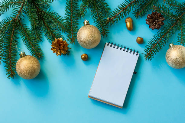 istock a notebook page with spruce branches, cones, golden balls and nuts on a blue background. top view. flat lay. mockup. 1346675354