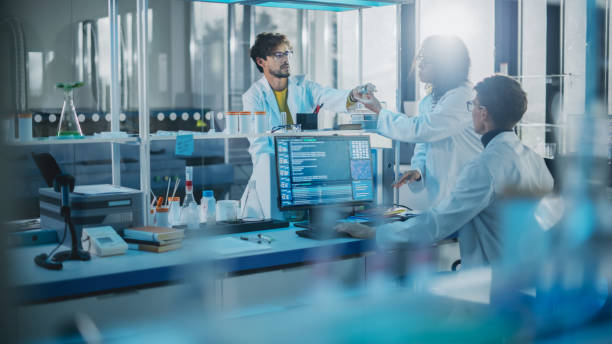 laboratoire de recherche en médecine moderne: une équipe diversifiée de jeunes scientifiques multiethniques passe des échantillons dans une boîte de pétri. laboratoire avancé avec équipement de haute technologie, des chercheurs en microbiologie con - biotechnology photos et images de collection