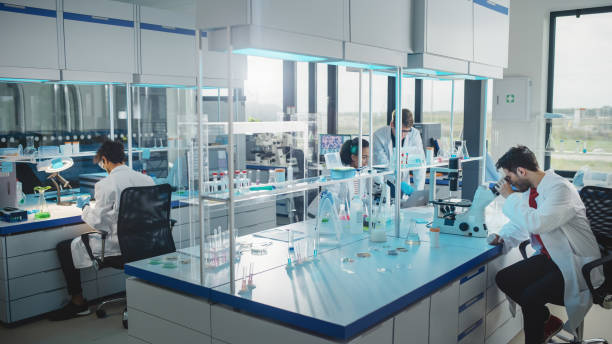 modern medicine laboratory: diverse team of multi-ethnic young scientists analysing test samples. advanced lab with high-tech equipment, microbiology researchers design, develop drugs, doing research - lab imagens e fotografias de stock