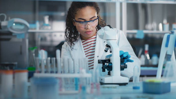 istock Medical Science Laboratory: Portrait of Beautiful Black Scientist Using Microscope, Does Analysis of Test Sample. Ambitious Young Biotechnology Specialist, working with Advanced Equipment 1346675603
