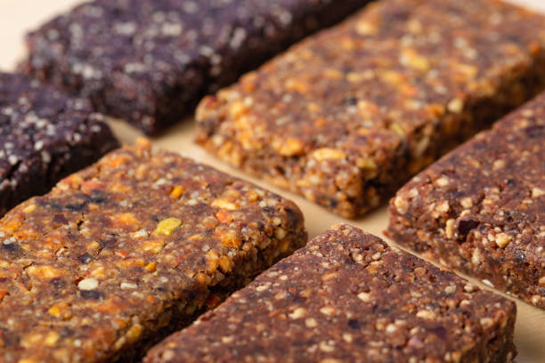Homemade granola bars with fine grinder nuts and dry fruits, organic super-food. Macro image with selective focus and very shallow DOF, side view on wooden surface.