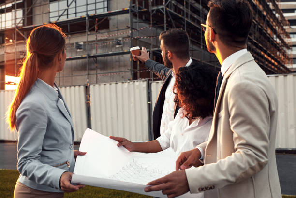 istock Business partners discussing a blueprint in front of the construction site. 1346675808