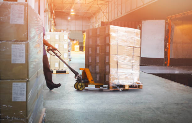 istock Worker Courier Unloading Package Box Out Of Cargo Container. Delivery service. Truck Loading at Dock Warehouse. Shipments Supply Chain. Shipping Warehouse Logistics Transportation. 1346676844