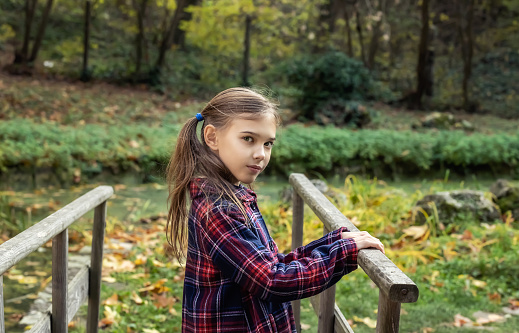 Portrait of a lovely little girl enjoys the beauty of an autumn in the park. Autumn mood.