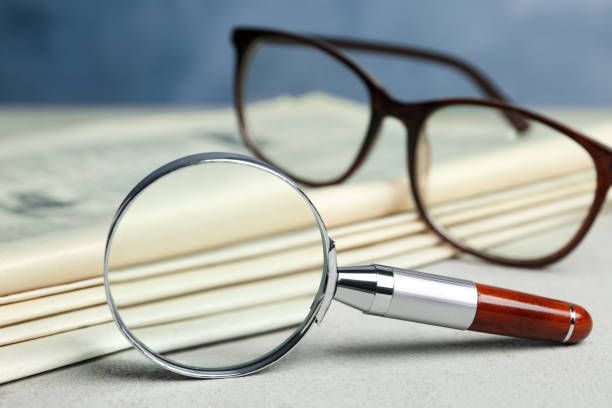 istock Stack of newspapers, magnifier and glasses on table. Search concept 1346680161