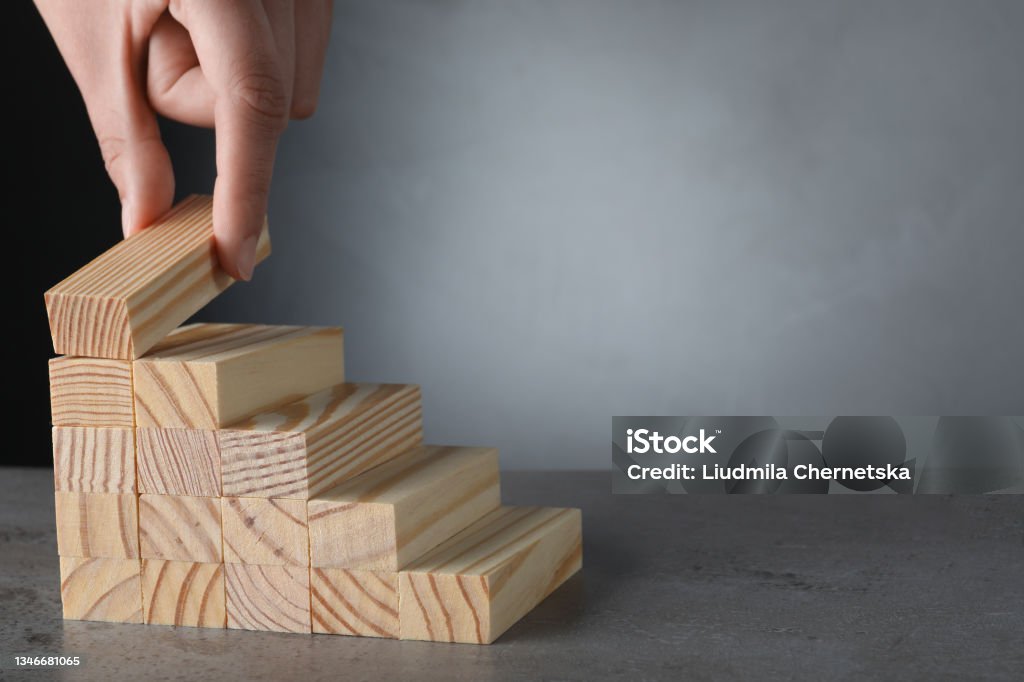 Nahaufnahme von Frauen, die Stufen mit Holzblöcken auf grauem Tisch bauen, Platz für Text. Karriereleiter - Lizenzfrei Aktivitäten und Sport Stock-Foto