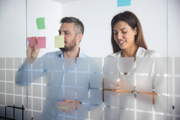istock Two colleagues writing details for kickoff meeting on adhesive notes 1346681114