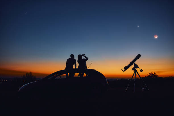 istock Couple stargazing together with a astronomical telescope. 1346683879