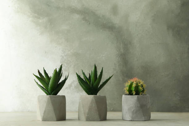 istock Artificial plants in flower pots on light grey stone table 1346683961