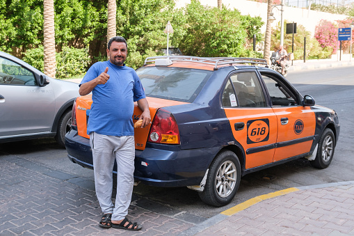 The driver of a city taxi waiting for passengers near an expensive hotel. City taxi in Hurghada, Egypt. Hurghada, Egypt - 10.14.2021
