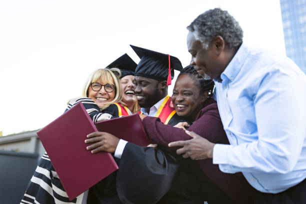 Emotional Graduation Moment. Mixed - race couple on graduation ceremony with their family