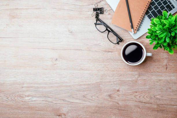 istock Work from home. desk office with laptop, blank notepad, coffee cup and pen on wood table. Flat lay top view copy spce. 1346687744