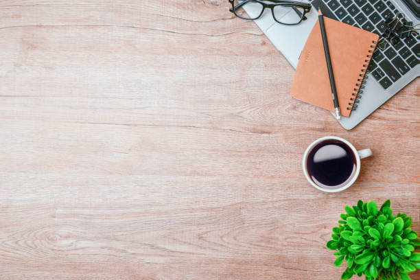 istock Work from home. desk office with laptop, blank notepad, coffee cup and pen on wood table. Flat lay top view copy spce. 1346687753