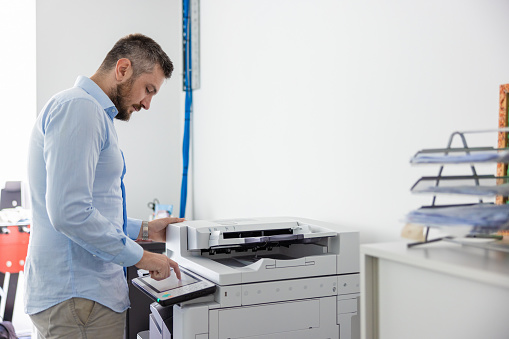 Office clerk pushing buttons for programming xerox in the office, copying documents