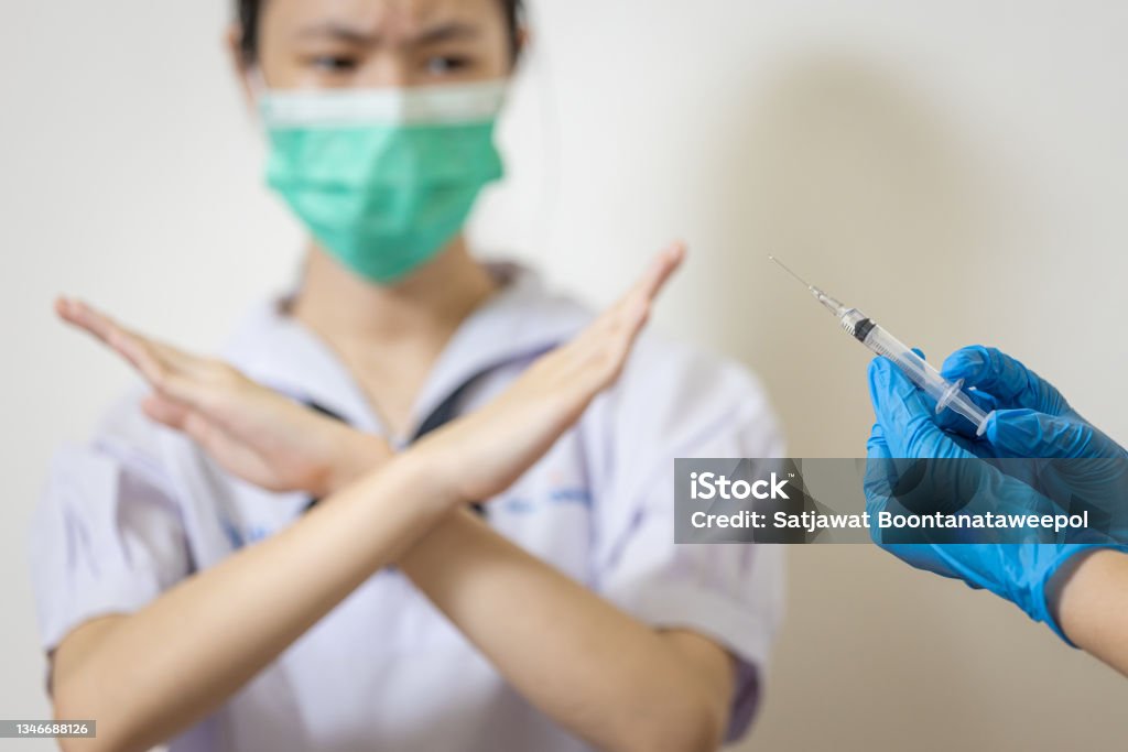 Hands of doctor preparing a syringe for injection to prevent Coronavirus,teenage girl with crossing hands gesture,asian student show distrust,refusing vaccine,dangers or side effects after vaccination Vaccination Stock Photo