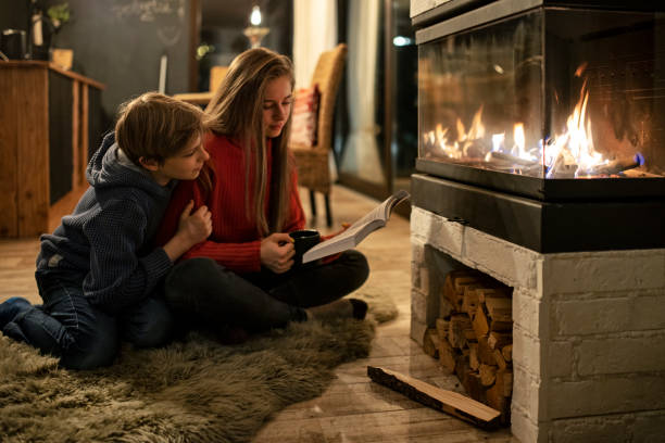 istock Brother and sister reading by the fireplace 1346690330