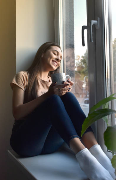 istock the girl sits on the windowsill and drinks coffee 1346690334
