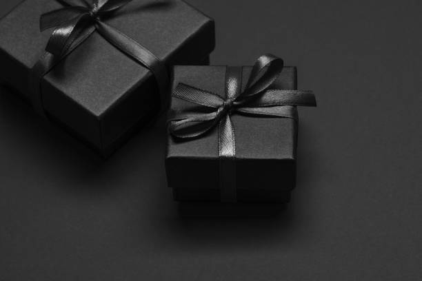 istock Black gift boxes tied with black ribbons on a black background. 1346690716