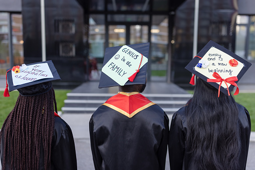 Graduation. Students after graduation ceremony holding their mortarboard with creative messages