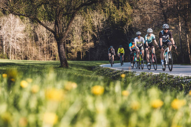 Group of cyclist cycling on a country road Group of people in colorful cycling clothes cycling on a sunny autumn day, on a country road with no cars. Road cycling in a group. Cycling stock pictures, royalty-free photos & images