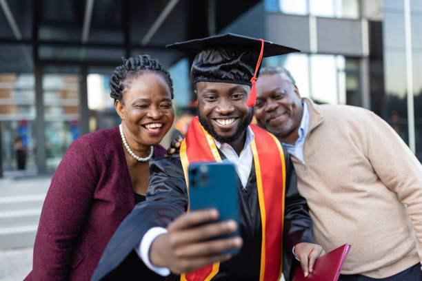 emocionado graduado universitario afroamericano con su familia después de la ceremonia de graduación - estudiante fotos fotografías e imágenes de stock