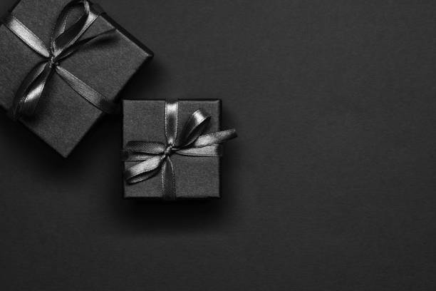 istock Black gift boxes tied with black ribbons on a black background. 1346691756