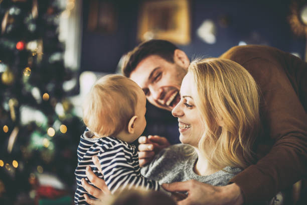 Happy parents having fun with their baby boy on New Year's day. Young happy parents having fun with their baby son during New Year at home. baby new years eve new years day new year stock pictures, royalty-free photos & images