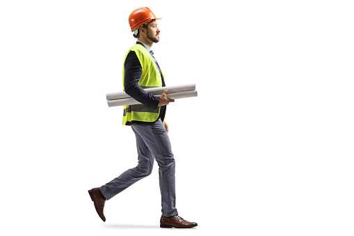Site engineer with a safety equipment walking and carrying blueprints isolated on white background