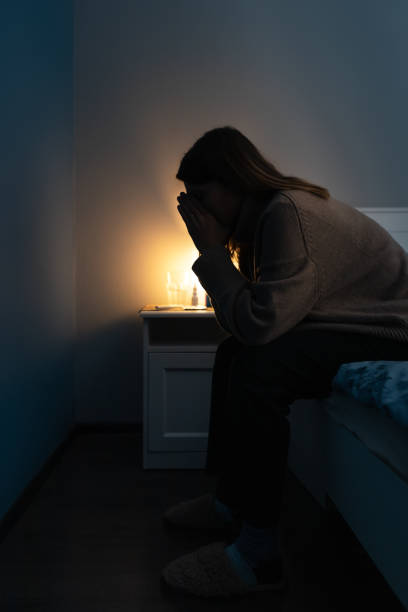 silhouette de femme priante assise sur le bord du lit. la femme met ses mains sur son visage et prie. fille fatiguée souffrant de rhume ou de grippe. - dark edge photos et images de collection