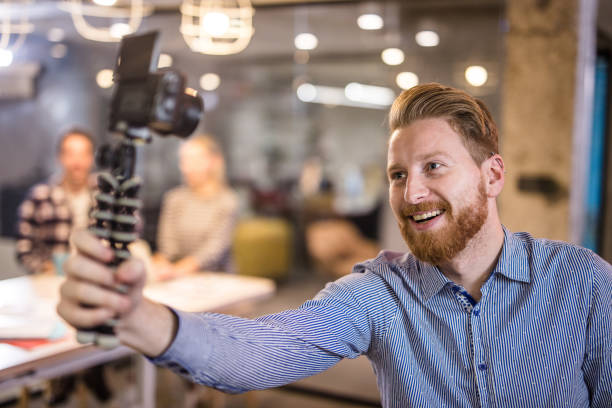 istock Young redhead businessman vlogging at casual office. 1346696993