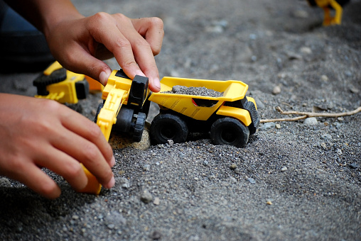 selective focus of small children playing with sand and truck, tractor and excavator toys