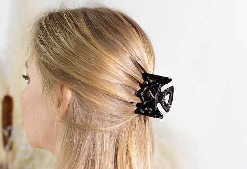 Black plastic pin barrette holding blonde hair