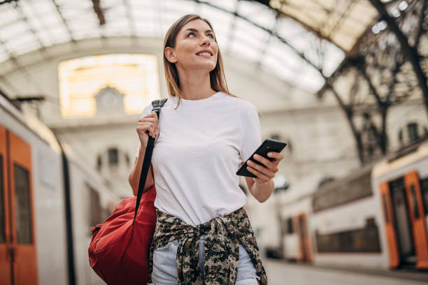 Woman going traveling One woman, beautiful young woman using smart phone at the train station. railroad station stock pictures, royalty-free photos & images