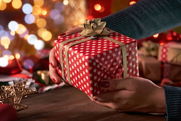istock Christmas themes: Woman hands giving a wrapped Christmas gift with copy space 1346705171