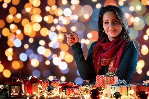 Christmas themes: Hispanic young woman pointing to the left side. Copy space \navailable